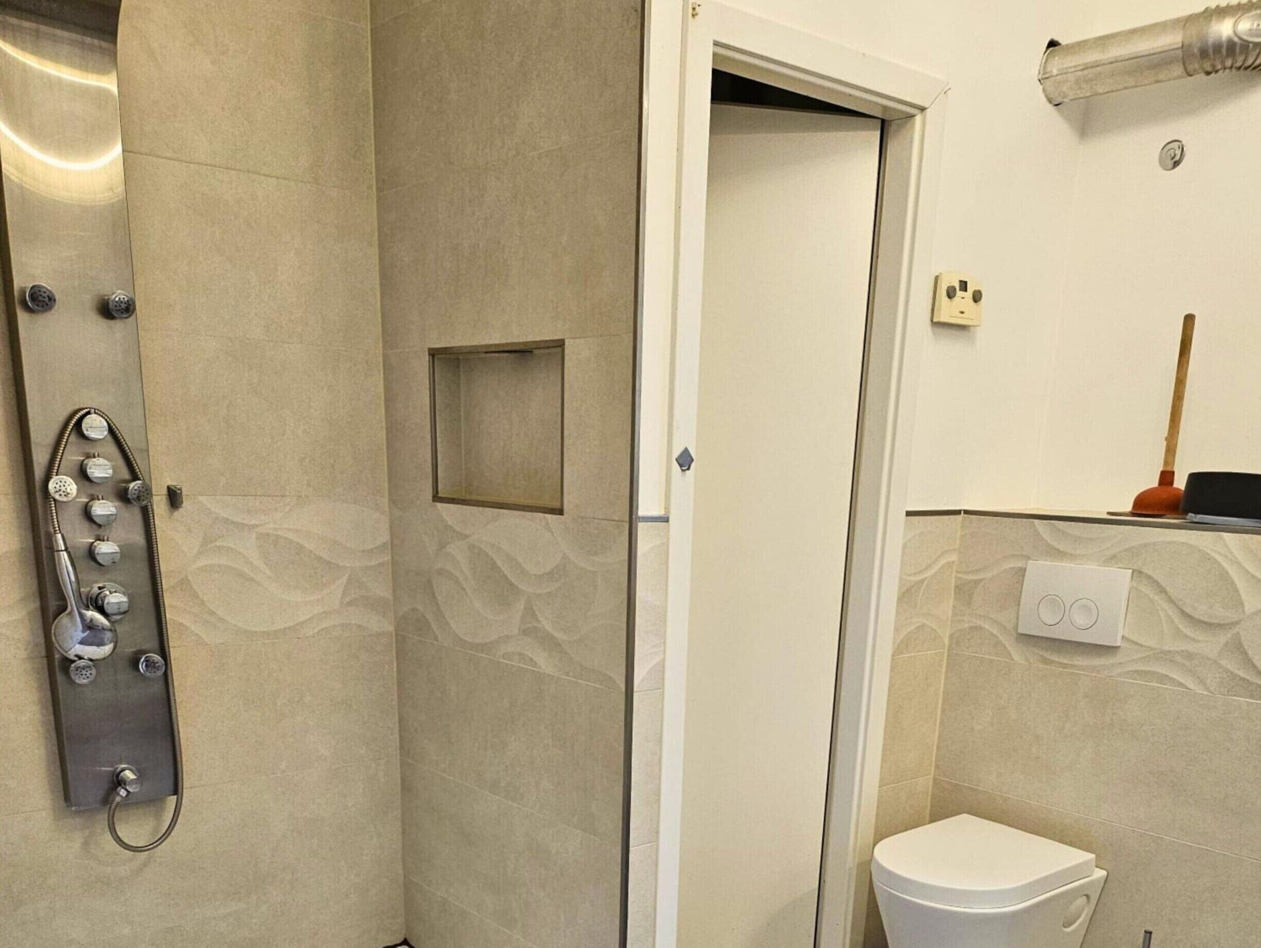 Un baño con ducha, inodoro y una pequeña ventana.