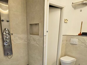 A bathroom with a shower, toilet, and a small window. - Modern Suite in the Taunus (Bad Camberg)