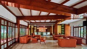 A spacious lobby with a high ceiling, wooden beams, and a central seating area with sofas and chairs. - Treat Imperial Jim Corbett (Ramnagar)