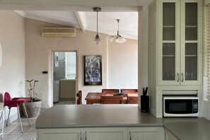 A kitchen with a large island, a microwave, and a dining area with a table and chairs. - Heritage Charmer | Roomy and cosy | Central Orange (Orange)
