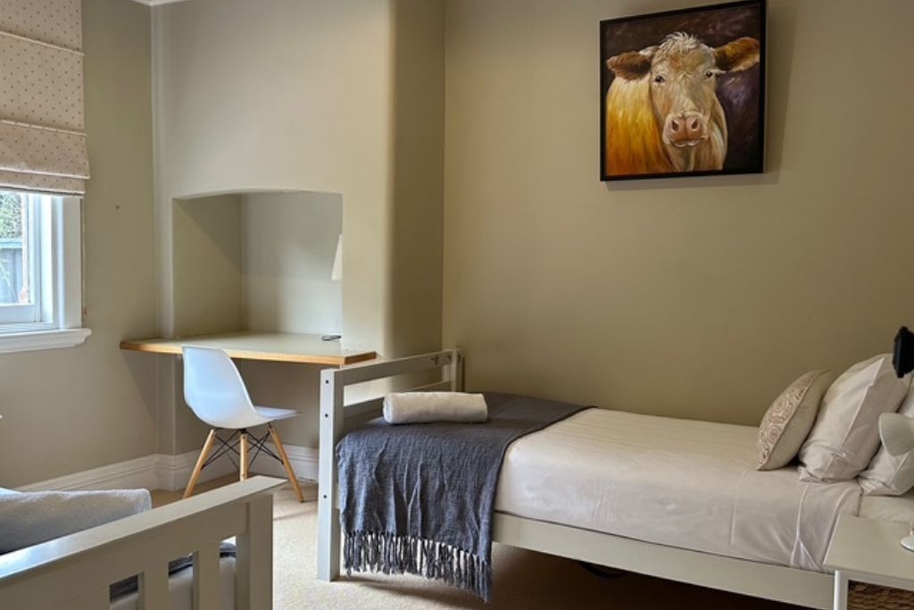 A bedroom with a bed, a desk, and a chair.