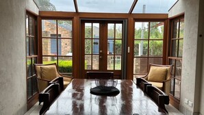 A dining area with a wooden table and chairs, large windows, and a view of a brick building. - Heritage Charmer | Roomy and cosy | Central Orange (Orange)