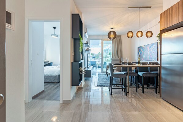 A modern kitchen with a dining area, a large window, and a view of the city. - Sunshine 1-BR Apt. & Blacony in Larnaca (Larnaca)