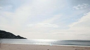 Uma praia com céu claro e mar calmo.