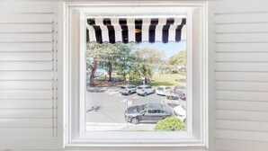 Ein Fenster mit Blick auf einen Parkplatz und Bäume.