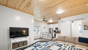 Ein modernes Interieur mit Fernseher, Küchenzeile und einer Couch.