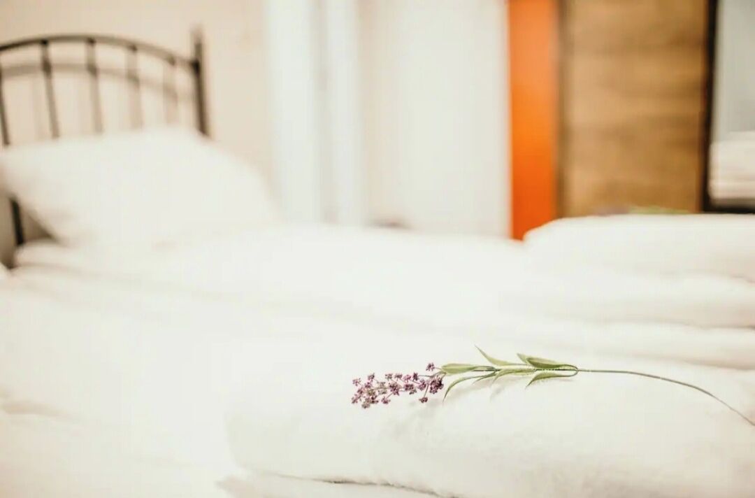 Een bed met witte lakens en een sierkussen met een bloemmotief.
