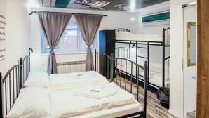 Ein Schlafraum mit Etagenbetten, einem Heizkörper, Vorhängen und einer Deckenleuchte.