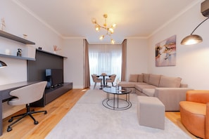Ein modernes Wohnzimmer mit einer Couch, einem Sessel, einem Couchtisch und einem Fernseher.