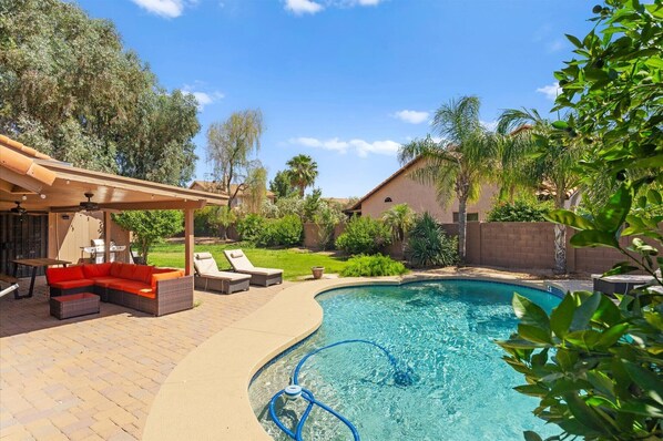 Ein Garten mit Pool, einer überdachten Terrasse und einer Lounge-Ecke.