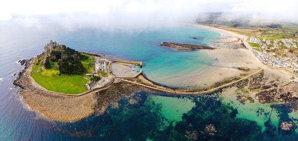 An aerial view of a coastal area with a castle, a beach, and a small town.