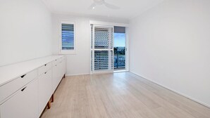 A room with a ceiling fan, a sliding glass door to a balcony, and a white dresser. - Coastal Luxe - Diamond Beach 168 (Mermaid Beach)