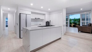 A modern kitchen with white cabinetry, a built-in oven, and a central island. - Coastal Luxe - Diamond Beach 168 (Mermaid Beach)