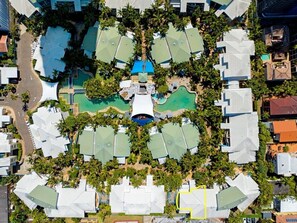 An aerial view of a resort with multiple buildings, a central pool area, and surrounding greenery. - Coastal Luxe - Diamond Beach 168 (Mermaid Beach)