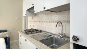 A kitchen with a gas stove, sink, and cabinets. - Porto Letizia Mascagni 1, Porlezza, Italy (Porlezza)