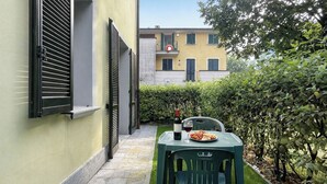 A narrow outdoor patio with a table set for two, a bottle of wine, and a plate of food. - Porto Letizia Mascagni 1, Porlezza, Italy (Porlezza)