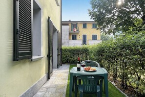 Eine schmale Außenveranda mit Tisch für zwei Personen, einer Weinflasche und einem Teller mit Essen.