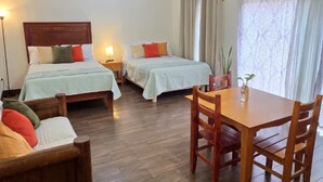 Une chambre d’hôtel avec deux lits, une table à manger et un plancher en bois.