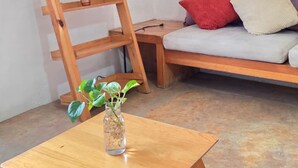 Une table en bois avec une plante, une échelle en bois et un canapé avec des coussins.