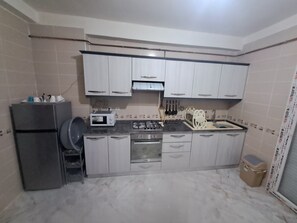 Una cocina compacta con refrigerador, microondas, estufa, horno y pileta con escurridor.
