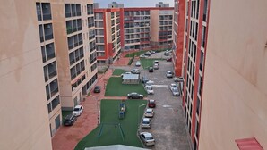 A multi-story residential building with a parking area, green spaces, and a solar panel structure. - Rental per night apartment f4 standing equipped (Tlemcen)