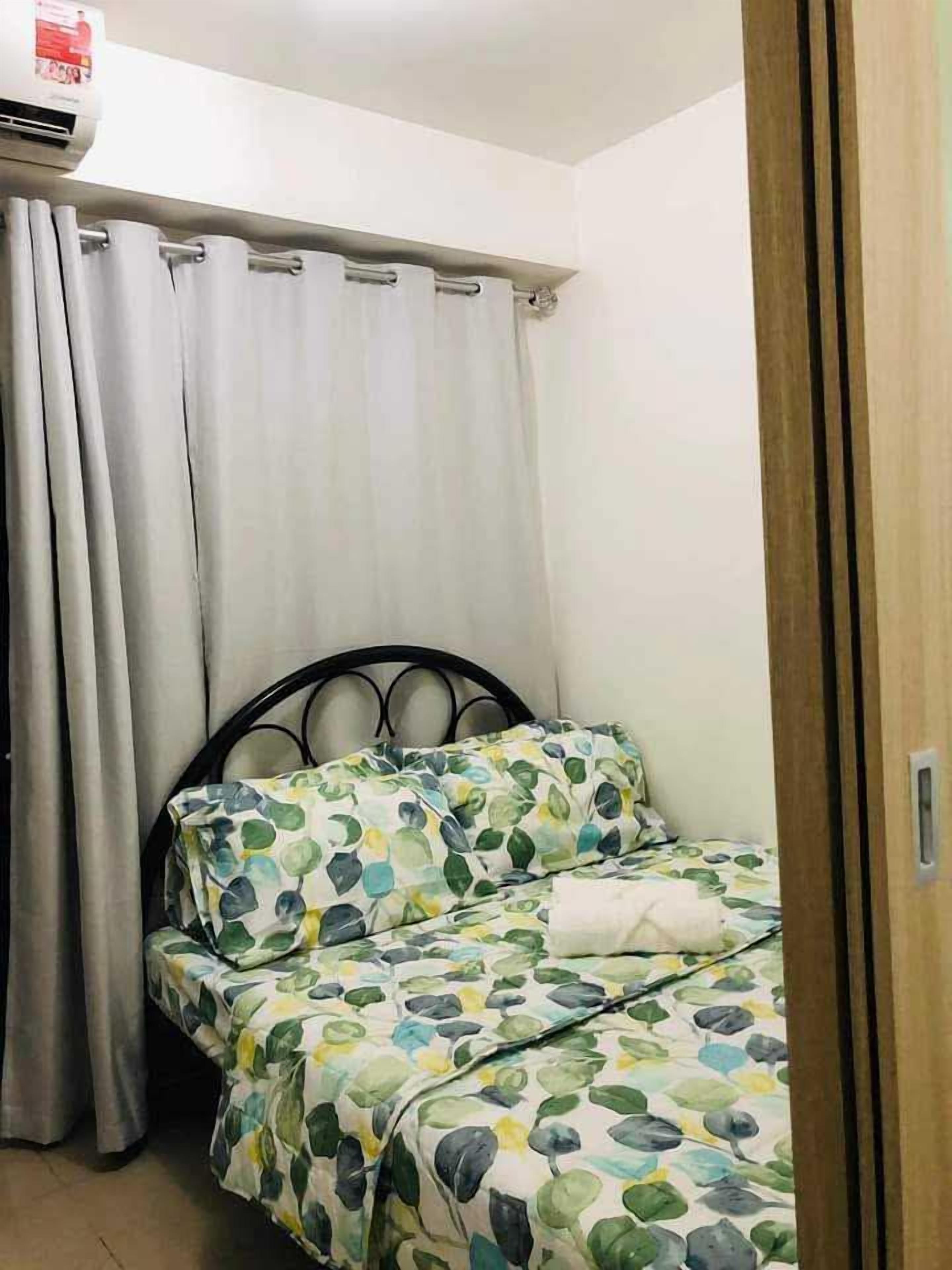 A bedroom with a bed, curtains, and a wooden door.