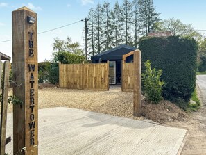 A wooden sign reading 'THE WATER TOWER' with a gravel driveway leading to a building with a dark roof and open doors. - 3 bedroom accommodation in Marlborough (Marlborough)