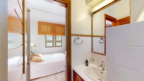 A hotel room with a bed, a bathroom with a sink and mirror, and a window with curtains. - Epidavros Villas, Elia Garden Retreat, Shared Pool (Nea Epidavros)