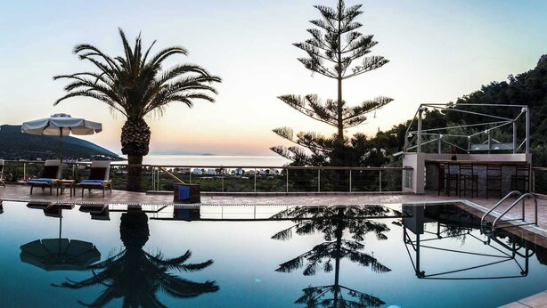 A pool area with lounge chairs, a palm tree, and a view of the mountains. - Epidavros Villas, Elia Garden Retreat, Shared Pool (Nea Epidavros)