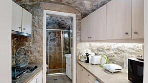Cocina compacta con paredes de piedra, ducha integrada y electrodomésticos modernos.