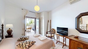 Une chambre à coucher avec un lit, une télévision, une commode et une chaise.