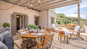 Un espace de restauration en plein air avec des tables et des chaises en bois, une pergola au-dessus et une vue sur un paysage montagneux.