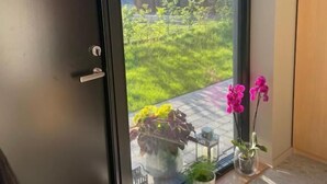 Ein Zimmer mit einer Schiebetür zum Garten, einem kleinen Tisch mit einem Blumentopf und einem dekorativen Gegenstand auf dem Boden.