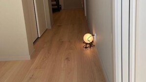 Ein Korridor mit Holzboden, einer Treppe und einer Wandleuchte.