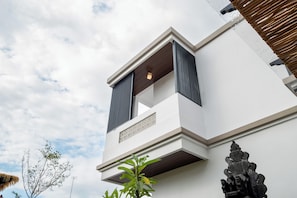 A modern building with a balcony, a small window, and a decorative stone structure.