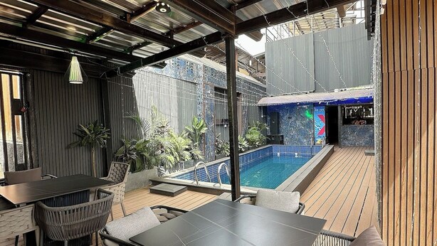 An outdoor patio with a pool, covered seating, and a view of the pool area. - Eseose Apartment (Abuja)