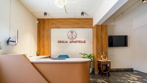 A reception desk with a wooden panel and a sign reading 'ODILIA APARTELLE.' - Odilia Apartelle (Bengaluru)