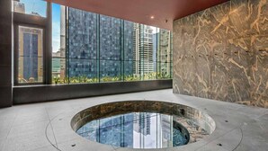 Un interno moderno con piscina a fondo trasparente al centro, ampie finestre e una parete in marmo.