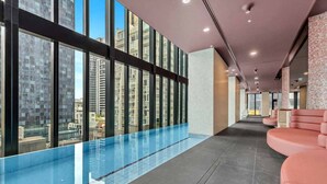 Una piscina interna moderna con barriera in vetro, ampie finestre e un corridoio con posti a sedere.