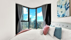 Una camera da letto con un letto grande, vista sulla città e un quadro appeso al muro.