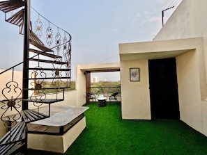 A modern outdoor space with a spiral staircase, a small seating area, and a view of the cityscape.