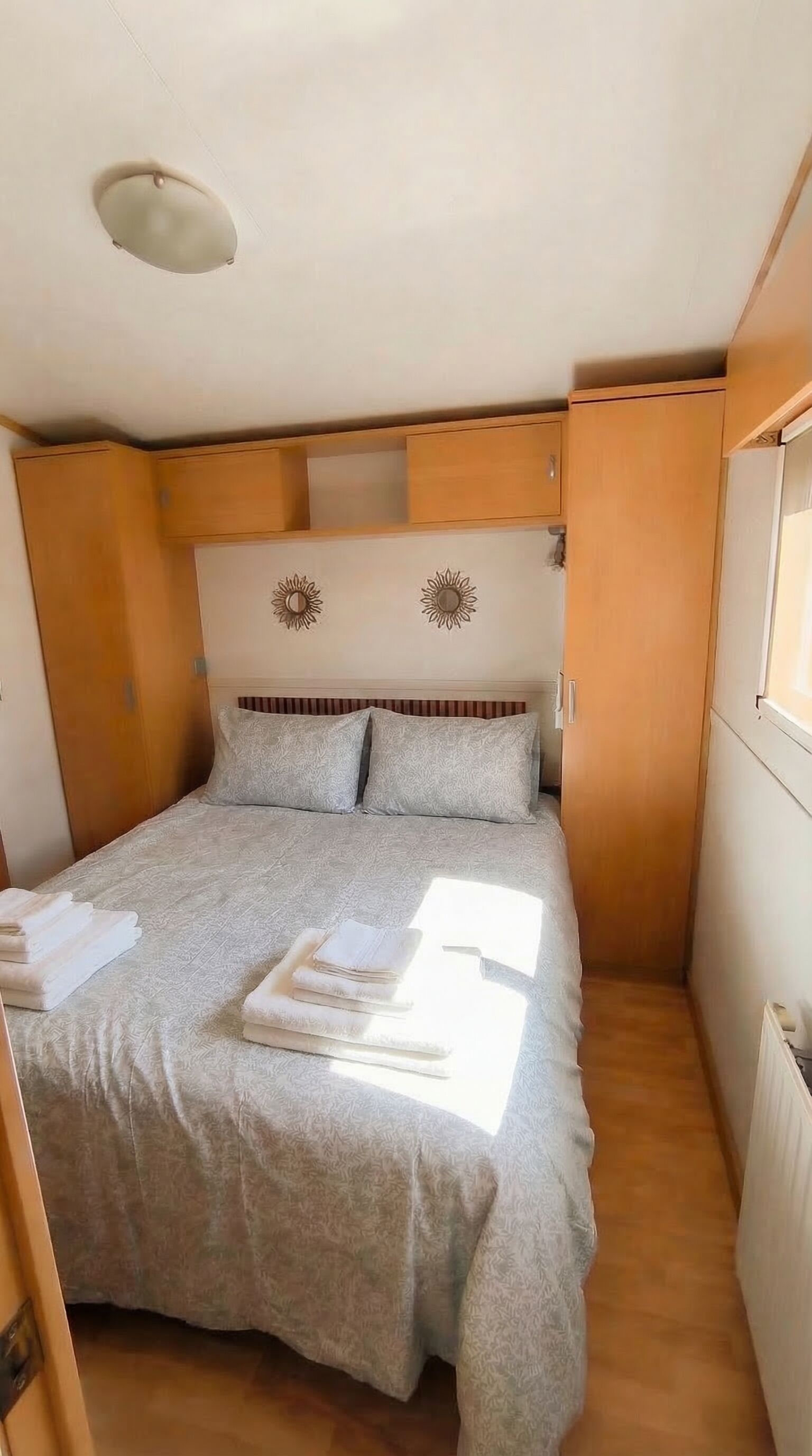 Un dormitorio pequeño con cama, almohadas, cabecera y ventana.