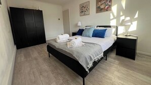 Ein Schlafzimmer mit Bett, Nachttischen, einem Kleiderschrank und Bildern an den Wänden.