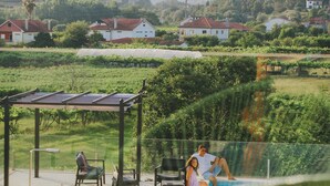 Uima-allasalue, jossa on pergola, tuoleja ja näkymä taloihin ja kukkuloille.