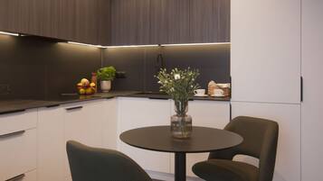 A modern kitchen with dark wood cabinets, a round table with two chairs, and a vase with flowers.