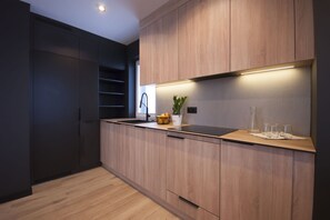 A modern kitchen with dark cabinetry, a wooden countertop, and a built-in sink.