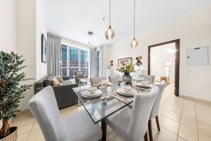 Et moderne spiseområde med et glasbord, hvide stole og udsigt over byen.