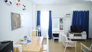 Ein Zimmer mit Holztisch, Stühlen, Schreibtisch, Fernseher und einer Karte an der Wand.