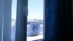 Ein Fenster mit Blick auf ein Gebäude, an dem ein Schild 'SM CITY TRECE MARTIRIES' befestigt ist.