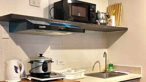 Une cuisine compacte équipée d’un four à micro-ondes, d’une bouilloire et d’un évier.